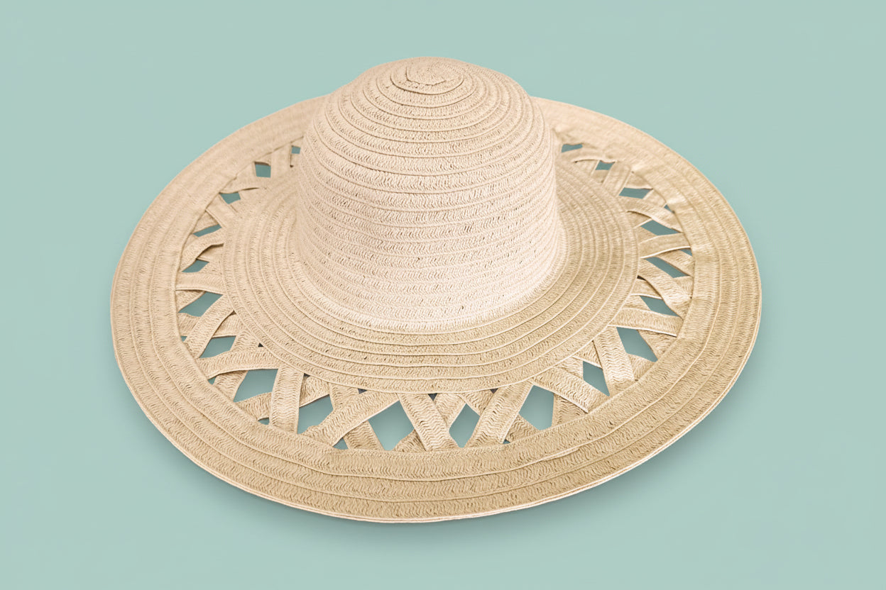 Beige straw hat with cut-out patterns on a white background